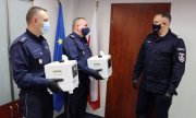 Trzej umundurowani policjanci z urządzeniami do dezynfekcji
