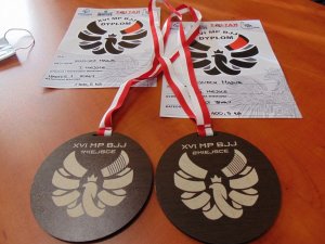 dwa medale i dwa dyplomy leżą na stole