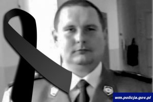 śp. asp. Marcin Opoński policjant Komendy Miejskiej Policji w Olsztynie w mundurze, z lewej strony zdjęcia kir żałobny