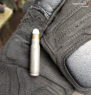 zdjęcie kolorowe: na dłoni ubranej w rękawiczkę umieszczono nabój do broni palnej