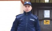 Na zdjęciu policjant w mundurze starszy sierżant Paweł Pyc stojący przed Komisariatem Policji w Twardogórze