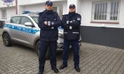 dwaj policjanci w mundurach stoją przed radiowozem