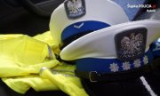 dwie policyjne czapki z białym otokiem leżące na żółtych kamizelkach