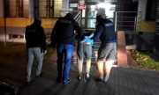 policjanci prowadzą zatrzymanego mężczyznę do budynku komendy policji