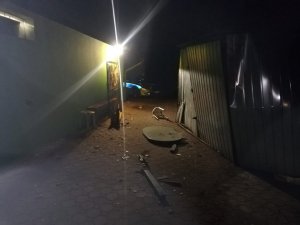 Uszkodzony blaszany garaż w tle radiowóz policyjny
