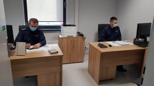 dwaj policjanci siedzą przy biurkach w nowej siedzibie posterunku