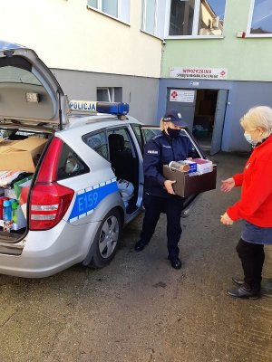 Policjantka przekazuje zebrane przez funkcjonariuszy produkty dla przedstawicielki Caritasu