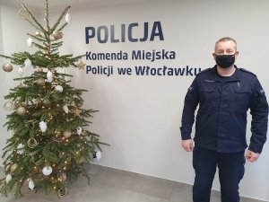 Dzielnicowy młodszy aspirant Peter Jonetzko stoi w budynku komendy policji, po lewej stronie stoi choinka świąteczna