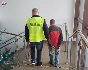 policjant prowadzący zatrzymanego mężczyznę po schodach
