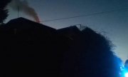 pora nocna, dym i ogień wydobywający się z komina, wozy służb ratunkowych z niebieskimi światłami uprzywilejowania
