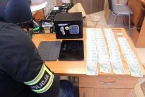 Policjant spisuje banknoty leżące na biurku
