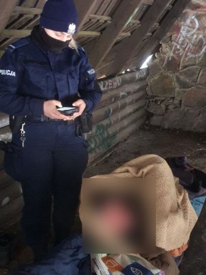 Policjantka stoi przy śpiącym mężczyźnie.