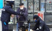 zdjęcie kolorowe: policjantka i policjant rozmawiający z seniorem wychodzącym ze sklepu z zakupami, którzy wręczają elementy odblaksowe