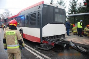 uszkodzony autobus stojący na przystanku autobusowym oraz policjanci i strażacy pracujący na miejscu zdarzenia