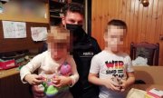 Policjant trzyma na kolanach dzieci z rodziny zastępczej, którą odwiedził