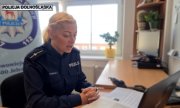 policjantka siedzi przy biurku, na którym stoi laptop