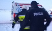Policjant i strażak wynoszą poszkodowanego na noszach
