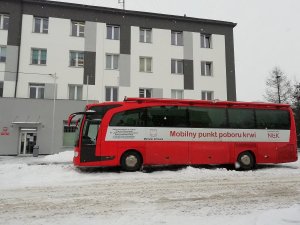 Na zdjęciu na tle budynku łęczyckiej komendy znajduje się biało-czerwony autobus z napisem „Mobilny punkt poboru krwi. Ministerstwo zdrowia”