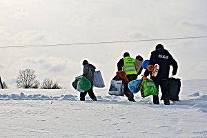 Dzielnicowy, żołnierz WOT, mężczyzna niosą torby przez zaśnieżone pole