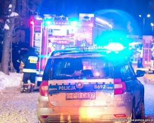 Radiowóz policyjny oraz wóz strażacki na sygnałach na miejscu zdarzenia