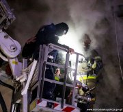 Policjant wraz ze strażakiem na koszu wysięgnika strażackiego pomagają w ewakuacji mężczyzny
