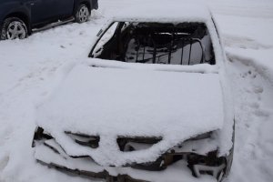 na zdjęciu samochód osobowy, który jest uszkodzony pokryty dużą warstwą śniegu. Pojazd posiada powybijane szyby&gt;