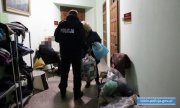 policjant przekazuje kobiecie paczki z ubraniami