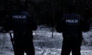 dwaj umundurowani policjanci w lesie - widok od tyłu
