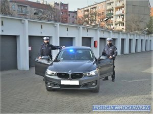 dwaj policjanci stoją obok radiowozu