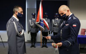 Komendant Wojewódzki Policji trzyma szablę stojąc naprzeciwko policjanta