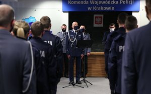 Policjanci stojący w szeregach, w głębi Komendant Wojewódzki Policji przemawia
