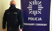Policjant stojący obok baneru z napisem Policja Pomagamy i Chronimy Komenda Powiatowa Policji w Jarosławiu
