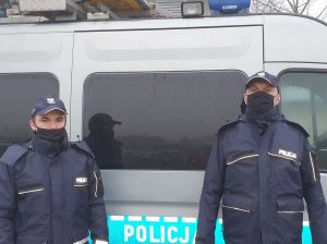 dwaj policjanci stoją przy radiowozie policyjnym