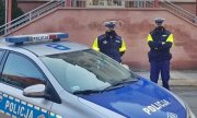 dwaj policjanci stoją obok radiowozu policyjnego zaparkowanego przed wejściem do szpitala