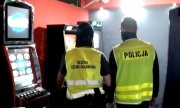policjant i funkcjonariusz służby celno-skarbowej stoją obok automatów do gier hazardowych