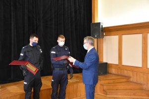 dwaj policjanci i burmistrz Miasta i Gminy Wieliczka wręczający policjantom podziękowania