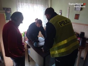 Policjanci wnoszący piec do mieszkania starszej osoby, której udzielili pomocy