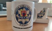 biały kubek z logo Komendy Powiatowej Policji w Sejnach