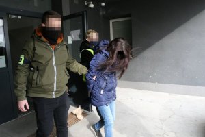 Policjanci po cywilnemu prowadzą zatrzymaną kobietę