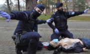 Dwaj policjanci nad leżącą osobą wykonują defibrylację za pomocą aede.