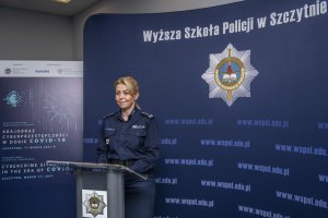Umundurowana policjantka - Komendant-Rektor WSPol stoi za mównicą i przemawia