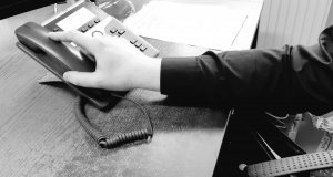 fragment ręki osoby sięgającej za słuchawkę telefonu - zdjęcie czarno-białe
