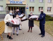 Trzy kobiety i mężczyzna przekazują policjantowi maskotki