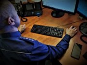 policjant siedzi przed ekranem komputera