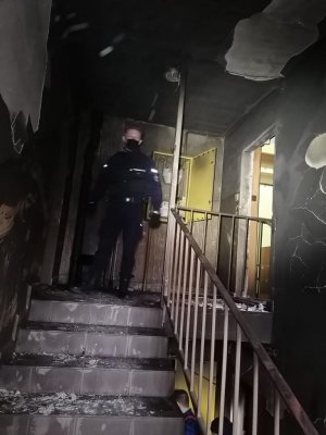 Spalona klatka schodowa w bloku gdzie wybuchł pożar oraz policjant z OPP Kraków