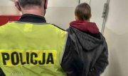 policjant w żółtej kamizelce z napisem Policja prowadzi zatrzymanego