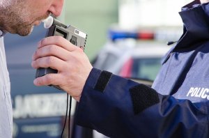 policjant bada zatrzymanego kierującego alkomatem