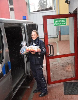 policjantka z świątecznymi prezentami w ręku przy furgonie policyjnym