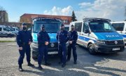 Czterej policjanci z Oddziału Prewencji Policji w Poznaniu, którzy uratowali 16-miesięczną dziewczynkę, na tle oznakowanego radiowozu.
