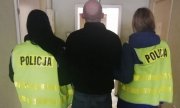 Policjantki prowadzą podejrzanego o kradzież korytarzem w jednostce Policji